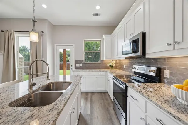 a kitchen with granite countertop a sink a counter space appliances and cabinets