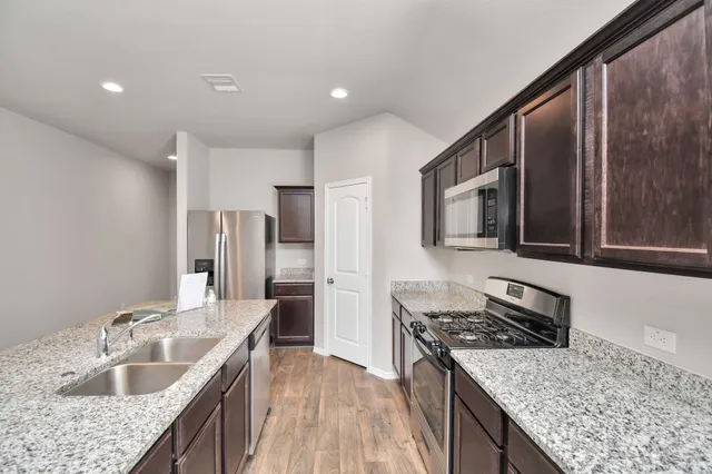 a kitchen with stainless steel appliances granite countertop a sink stove and refrigerator