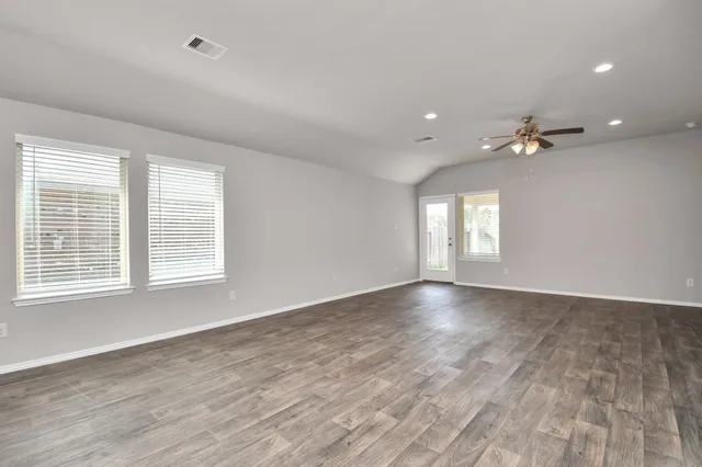 a view of an empty room with a window and wooden floor