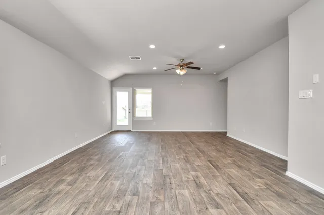 a view of an empty room with wooden floor and a window
