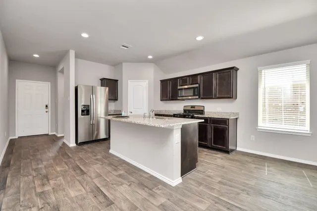 a kitchen with stainless steel appliances kitchen island granite countertop a stove a sink and a refrigerator
