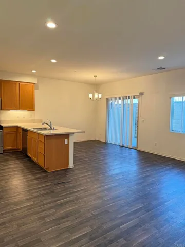 a view of a kitchen with kitchen island a sink wooden floor and a refrigerator