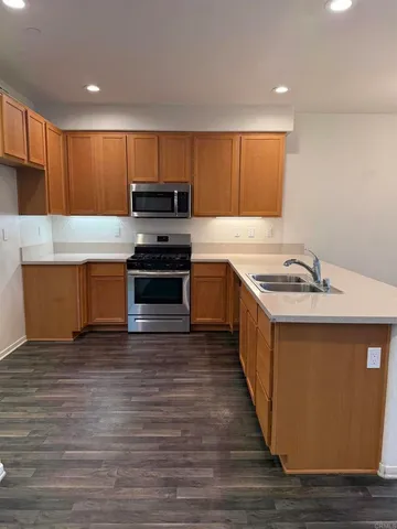 a kitchen with stainless steel appliances granite countertop a sink a stove and a wooden floors
