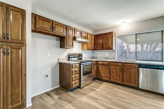 a kitchen with stainless steel appliances granite countertop a stove a sink and a refrigerator