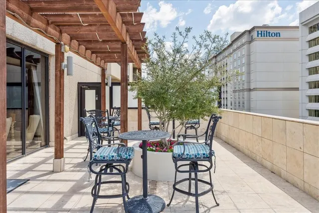 a patio with table and chairs and potted plants