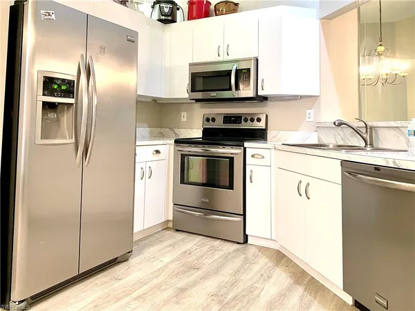 a kitchen with granite countertop a refrigerator stove and microwave