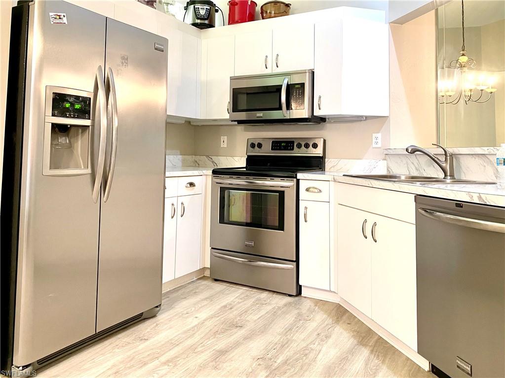 3745 Fieldstone Boulevard, Unit 107 Naples, FL 34109 - Photo 7 of 14 a kitchen with granite countertop a refrigerator stove and microwave