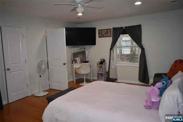 a bedroom with a bed and a flat tv screen on dresser