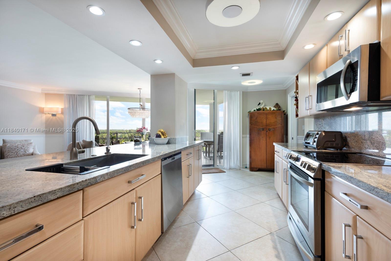 4000 Towerside Terrace, Unit 1005 Miami, FL 33138 - Photo 13 of 25 a kitchen with stainless steel appliances granite countertop a sink and a stove top oven with wooden floor