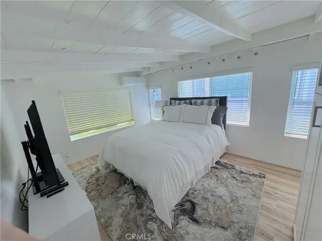 a bedroom with a bed a dresser next to a window