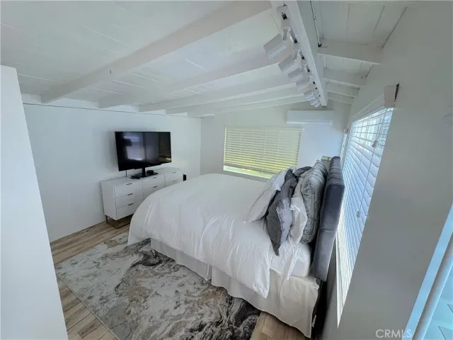 a bedroom with a bed and flat tv screen on the dresser