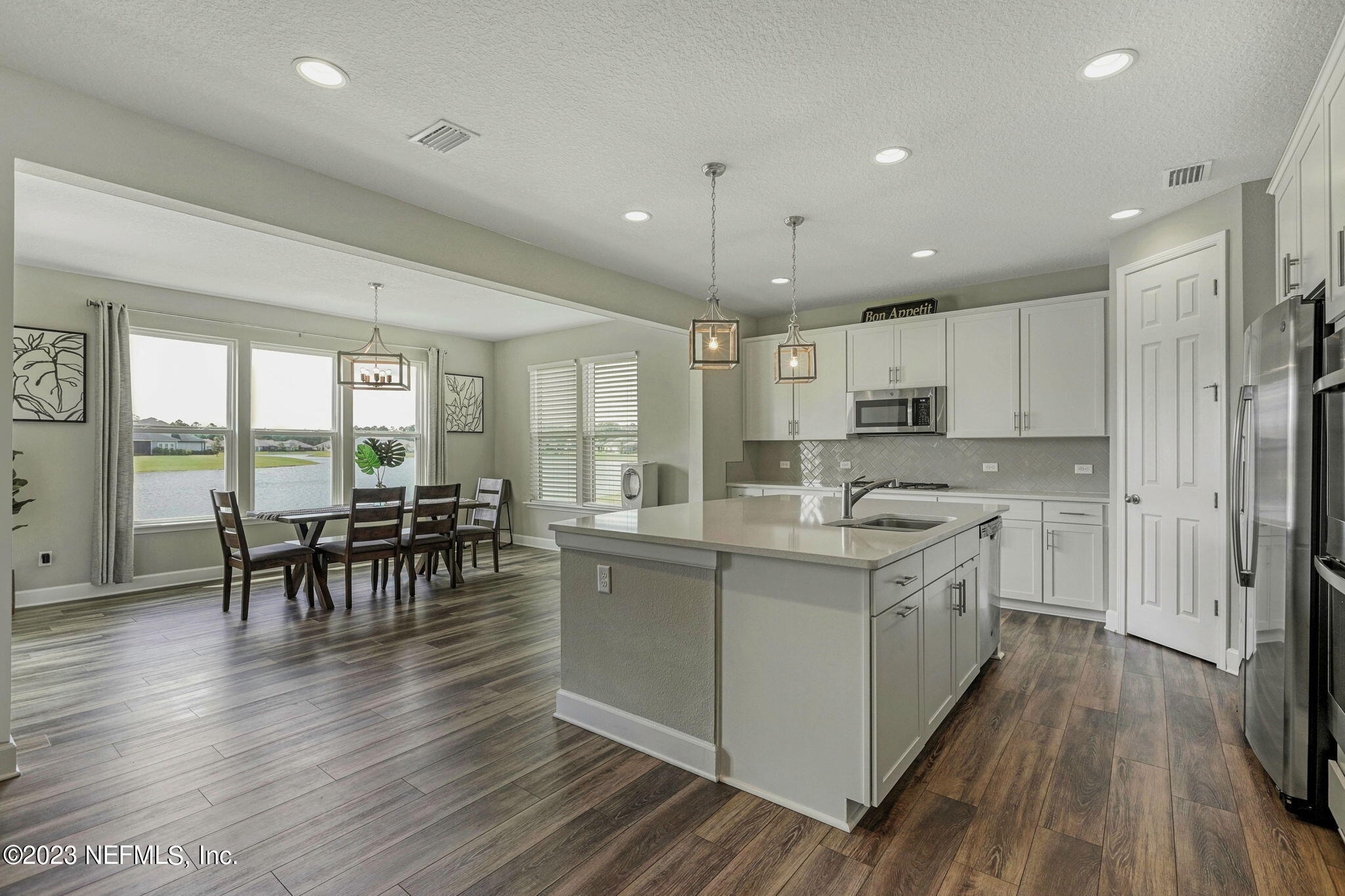 69 Willow Lake Drive St. Augustine, FL 32092 - Photo 6 of 42 a kitchen with stainless steel appliances granite countertop a stove oven a refrigerator a dining table and chairs with wooden floor
