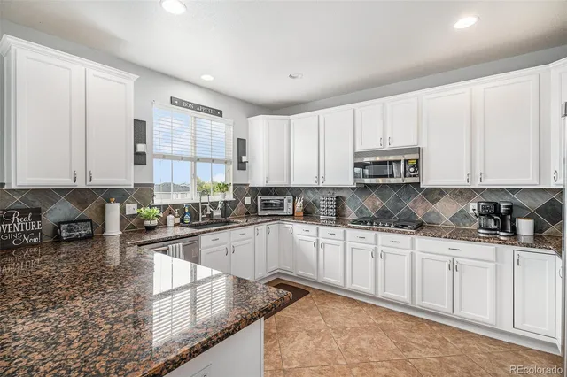 a kitchen with kitchen island granite countertop a sink a stove and cabinets
