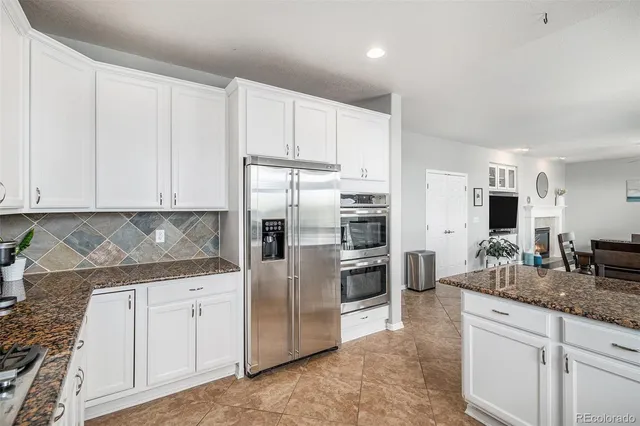 a kitchen with granite countertop white cabinets and stainless steel appliances