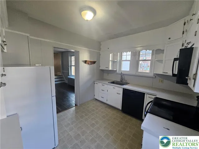 a large kitchen with a refrigerator a sink dishwasher a stove and a refrigerator with wooden floor