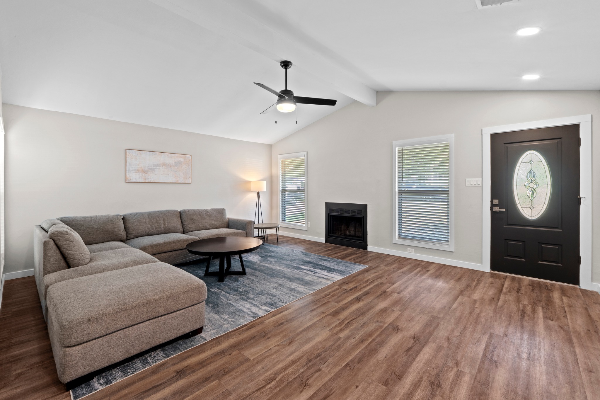 11811 Rotherham Drive Austin, TX 78754 - Photo 6 of 37 Enter into an inviting living room featuring vaulted ceilings, a cozy fireplace, and durable wood flooring.
