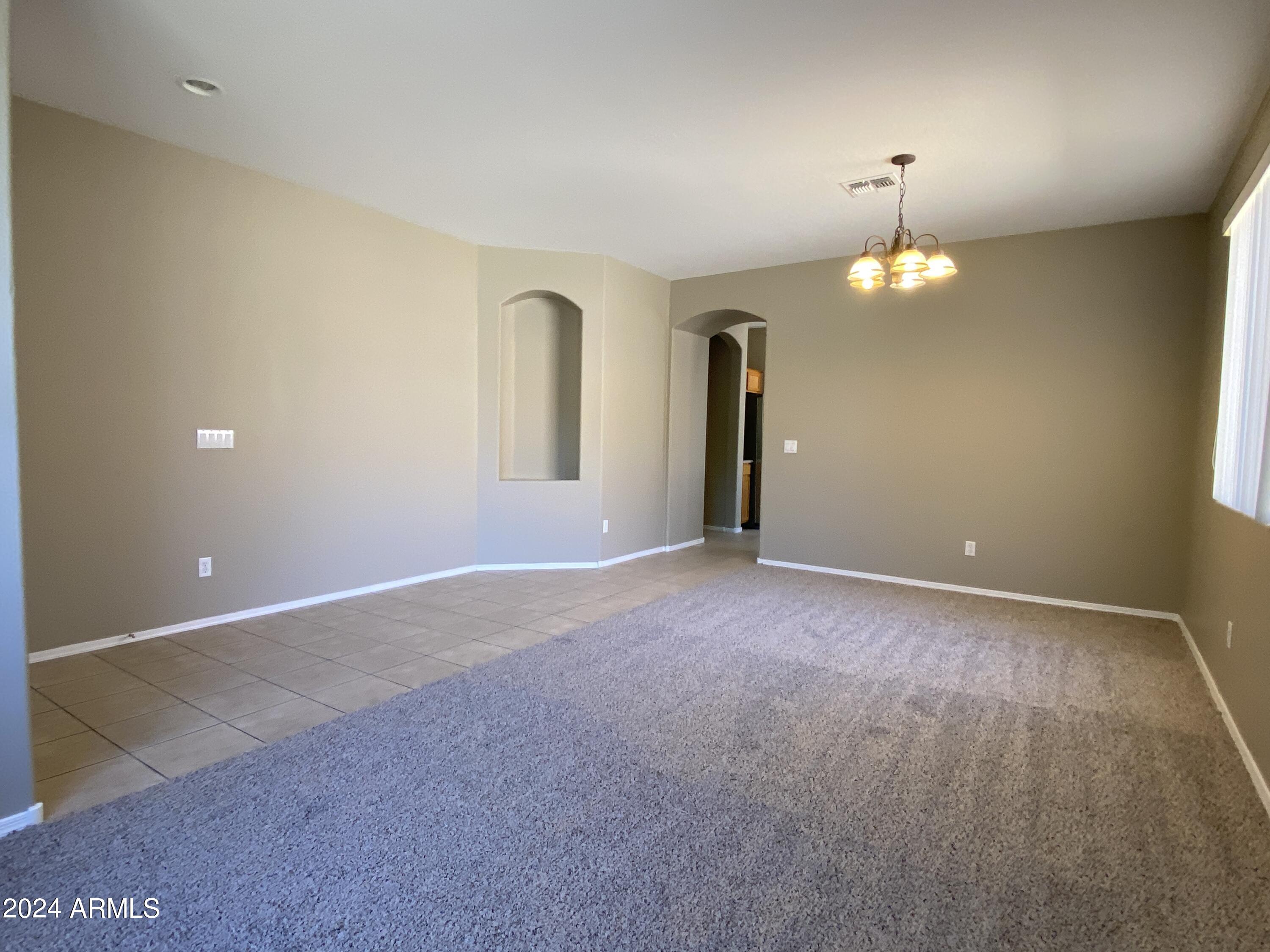 7217 West Kings Avenue Peoria, AZ 85382 - Photo 4 of 19 an empty room with a chandelier fan and a window