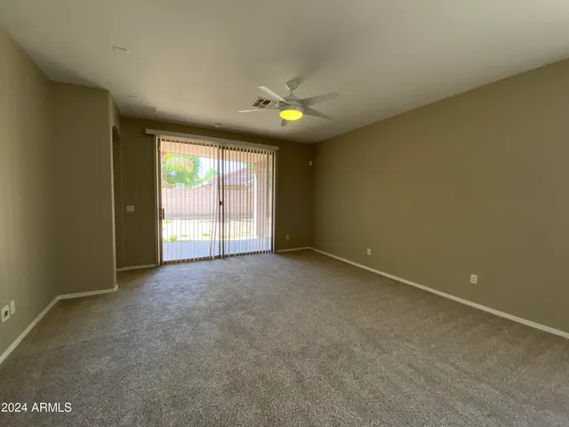 an empty room with a window and chandelier fan