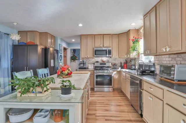 a kitchen with stainless steel appliances granite countertop a refrigerator sink stove microwave and cabinets
