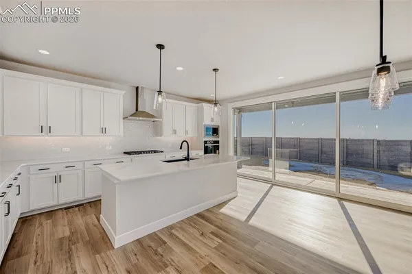 a large white kitchen with white cabinets and wooden floor