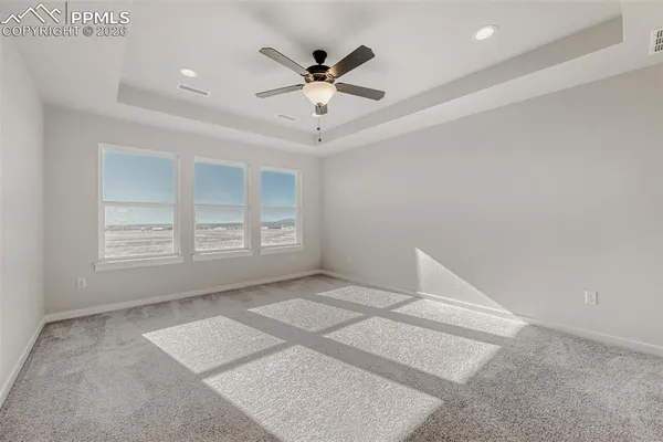 an empty room with windows and ceiling fan