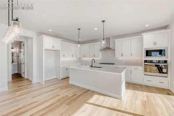 a large white kitchen with kitchen island a sink stainless steel appliances and cabinets