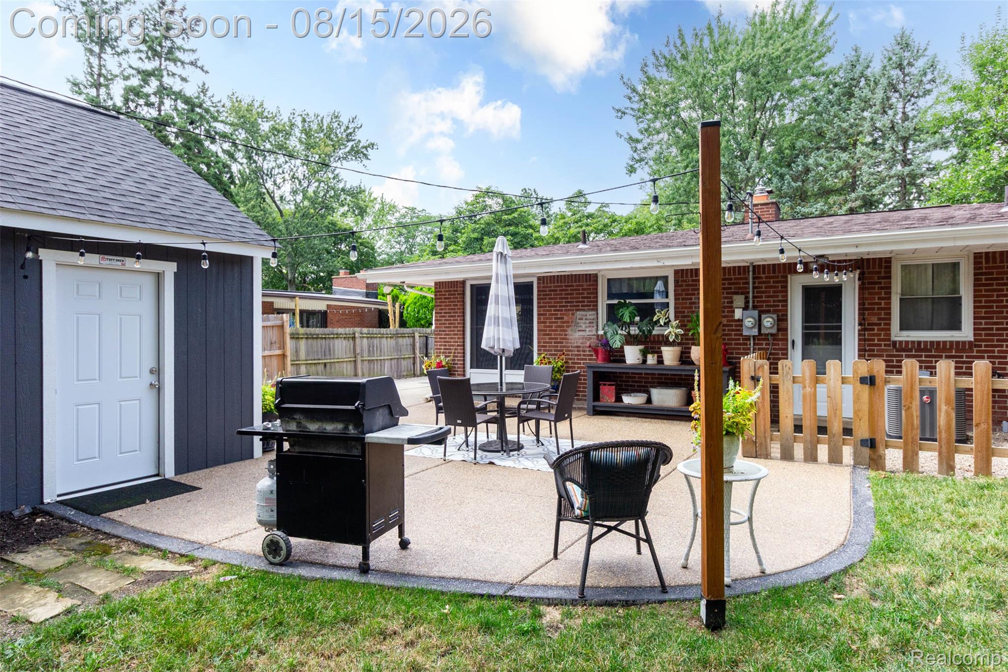 29604 Chelmsford Road Southfield, MI 48076 - Photo 37 of 39 Expansive patio with a curved edge, brick exterior, dedicated storage structure, and string lighting