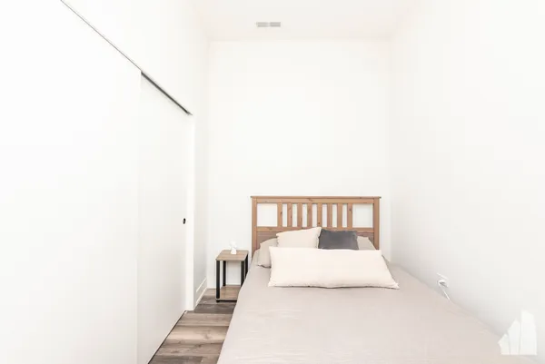 a bedroom with a white bed and a lamp with potted plant