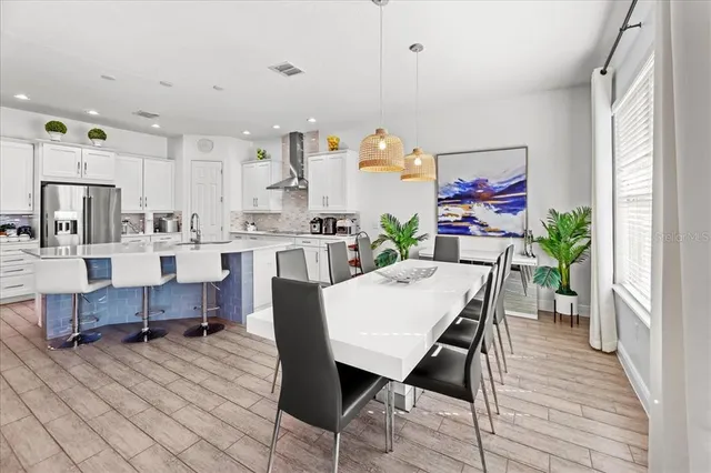 a kitchen with stainless steel appliances a table chairs refrigerator and sink