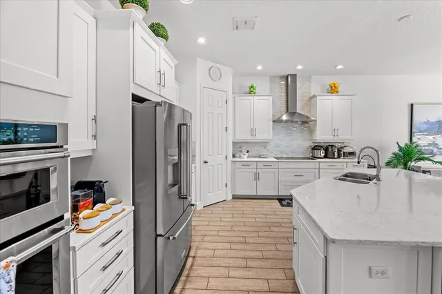 a large white kitchen with a large window and stainless steel appliances