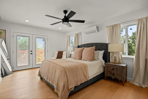a spacious bedroom with a bed a large window and a chandelier