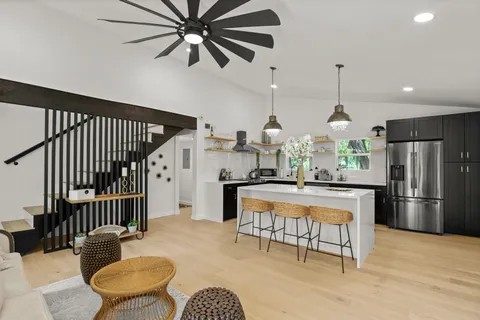 a kitchen with stainless steel appliances kitchen island granite countertop a refrigerator a stove a microwave oven a dining table and chairs with wooden floor