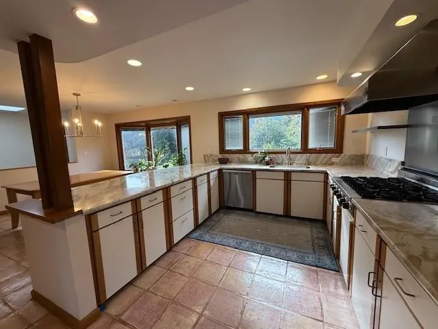 a large kitchen with stainless steel appliances granite countertop a stove and a sink