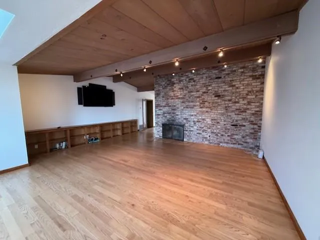 a view of empty room with wooden floor and fireplace