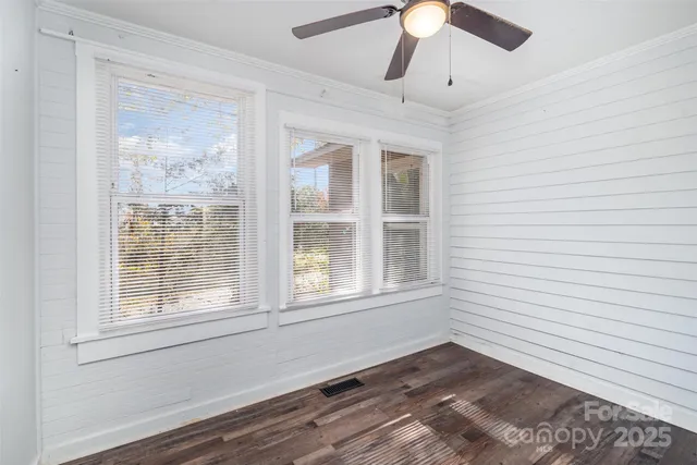 a view of an empty room with a window and wooden floor
