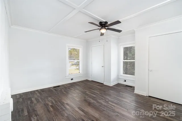 an empty room with wooden floor fan and windows
