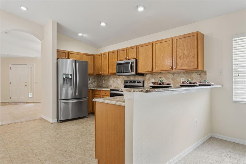 25932 Terrawood Loop Land O Lakes, FL 34639 - Photo 5 of 28 a kitchen with stainless steel appliances granite countertop a refrigerator a stove a sink a microwave a oven and a refrigerator with wooden floor