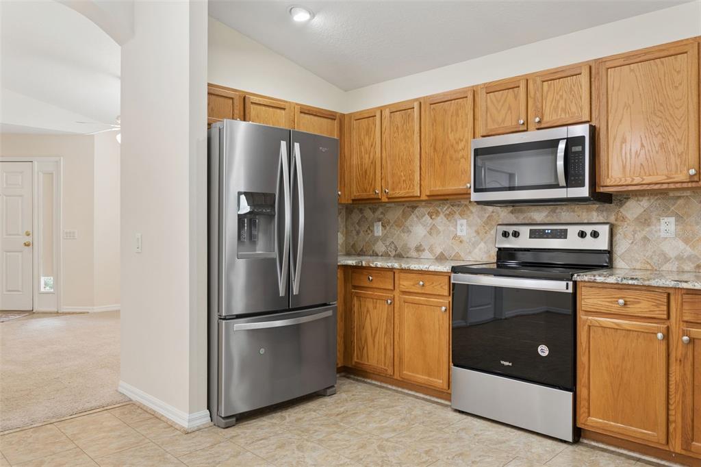 25932 Terrawood Loop Land O Lakes, FL 34639 - Photo 6 of 28 a kitchen with stainless steel appliances granite countertop a refrigerator stove and microwave