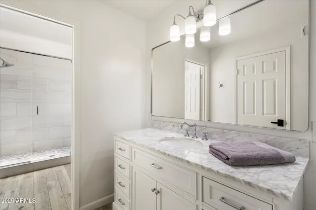 a bathroom with a granite countertop sink a light fixture and a mirror