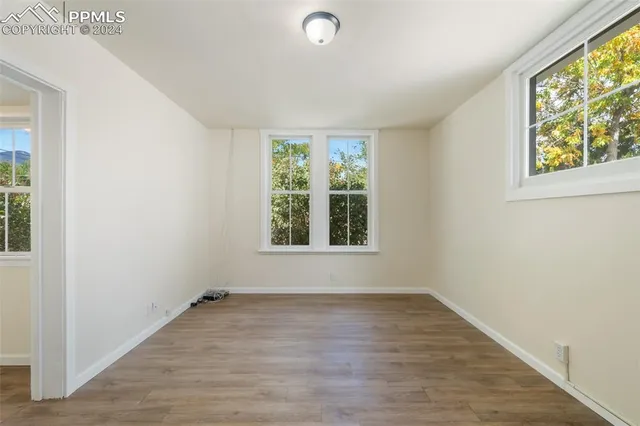 an empty room with wooden floor and windows