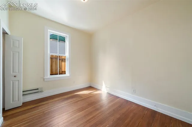 a view of an empty room with wooden floor and a window