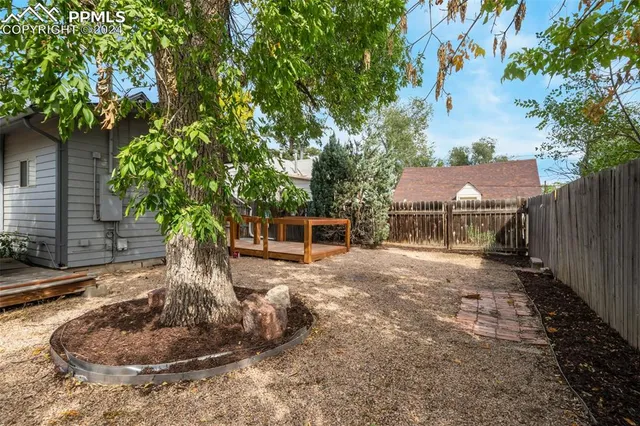 a backyard of a house with table and chairs under an umbrella