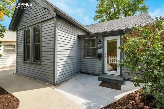 a view of a brick house with a small yard and wooden fence