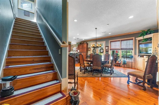 a kitchen with stainless steel appliances granite countertop a stove a refrigerator a sink a dining table and chairs with wooden floor