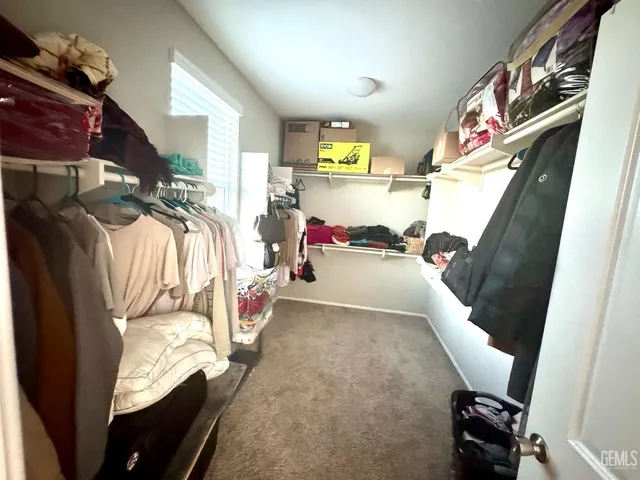 a view of walk in closet with clothes and shoes
