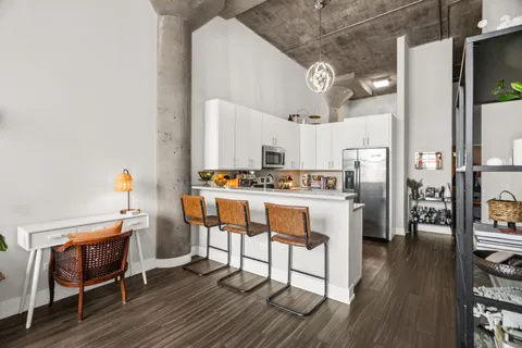 a kitchen with stainless steel appliances kitchen island granite countertop a table chairs stove and white cabinets