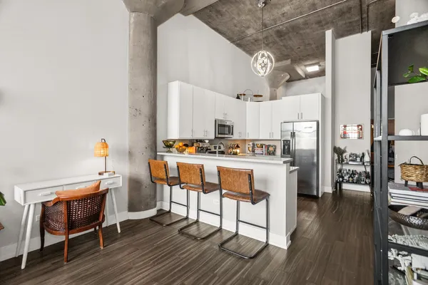 a kitchen with stainless steel appliances kitchen island granite countertop a table chairs stove and white cabinets