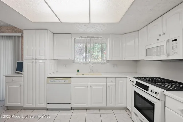 a kitchen with a sink a counter top space appliances and cabinets