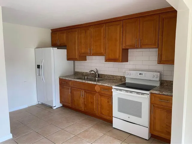 a kitchen with granite countertop wooden cabinets and white appliances
