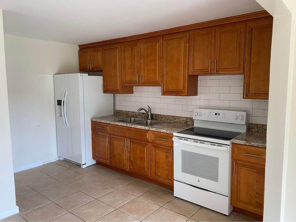 3952 Northwest 83rd Lane Coral Springs, FL 33065 - Photo 2 of 10 a kitchen with granite countertop wooden cabinets and white appliances